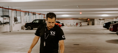 A male worker in a black CleanSpace shirt walking through a parking garage.