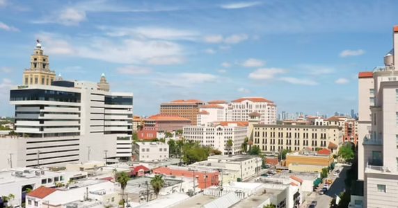 Aerial view of Coral Gables architecture and city buildings under a partly cloudy sky.