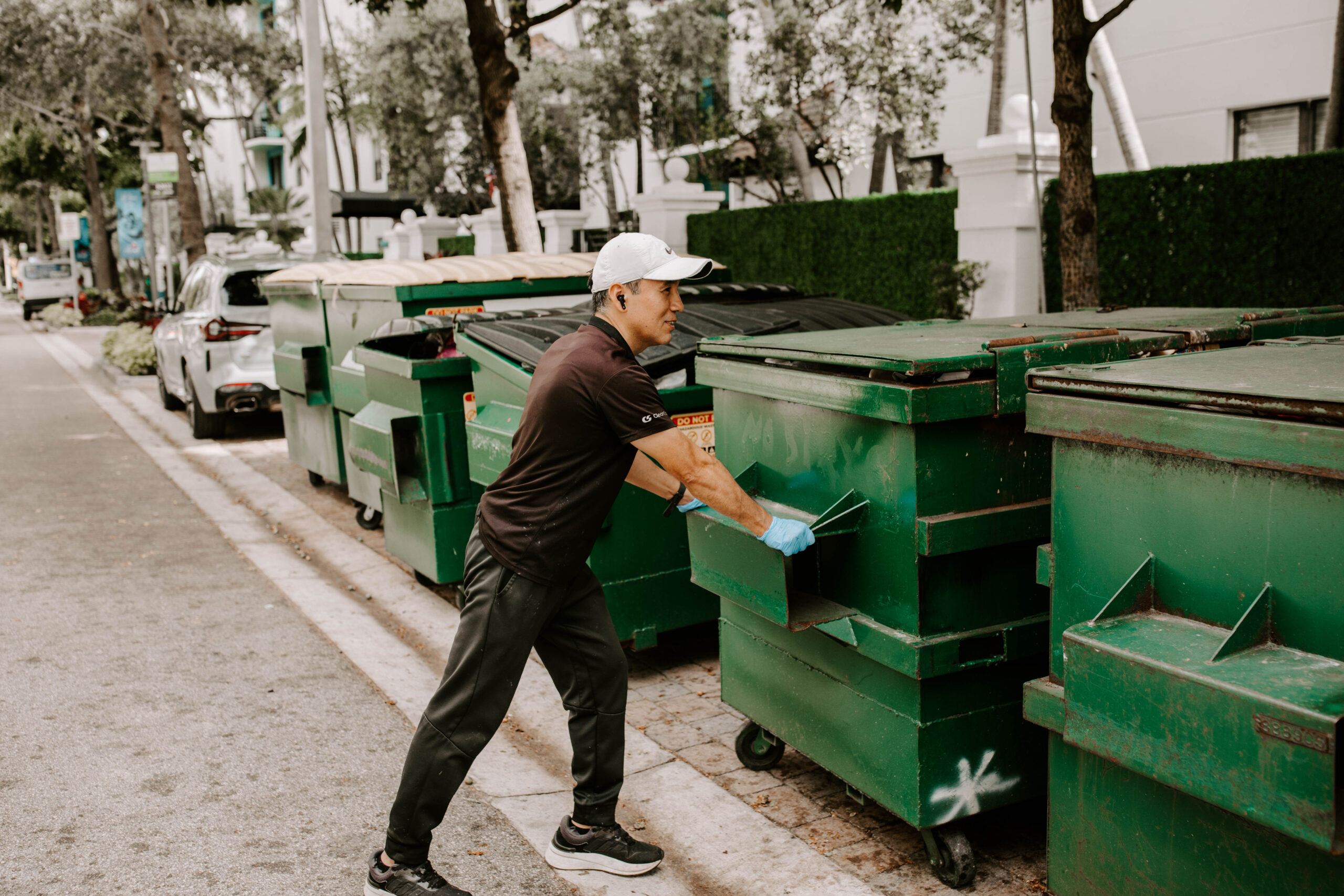 Clean Space porter closing a dumpster lid at a Florida commercial property