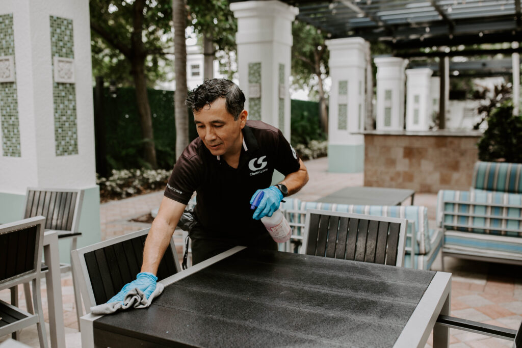 Clean Space cleaner wiping an outdoor dining table on a Florida pool deck